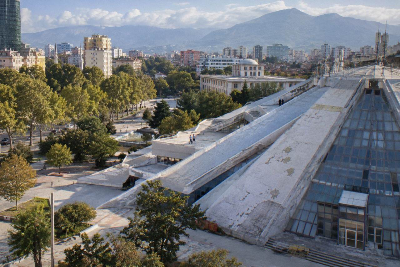 The stepped exterior of the Pyramid of Tirana rising above the surrounding park and city rooftops