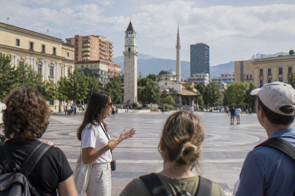 A guide speaking to a small group of visitors on a walking tour in central Tirana