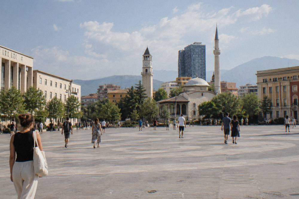 Visitors walking across Skanderbeg Square in central Tirana on a sunny afternoon