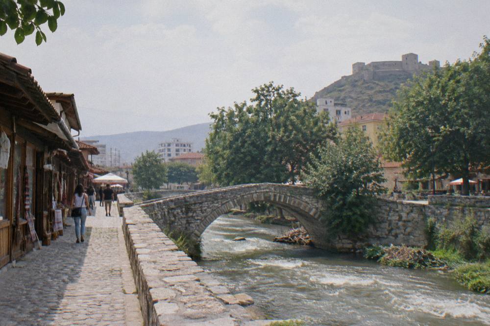 Cobbled bazaar street with wooden shopfronts leading toward Kruja Castle in Albania