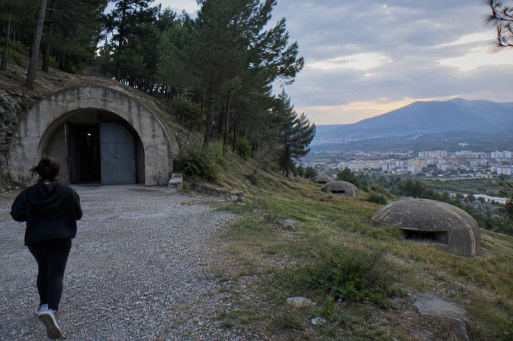 A row of small concrete bunker domes on a grassy slope overlooking a valley