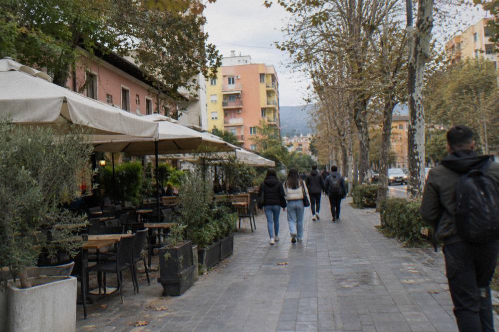 People walking along a tree-lined street in the Blloku district of Tirana in the late afternoon