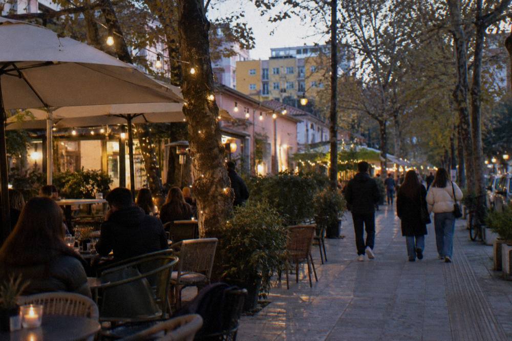 Cafe tables and string lights on a tree-lined street in the Blloku district at night