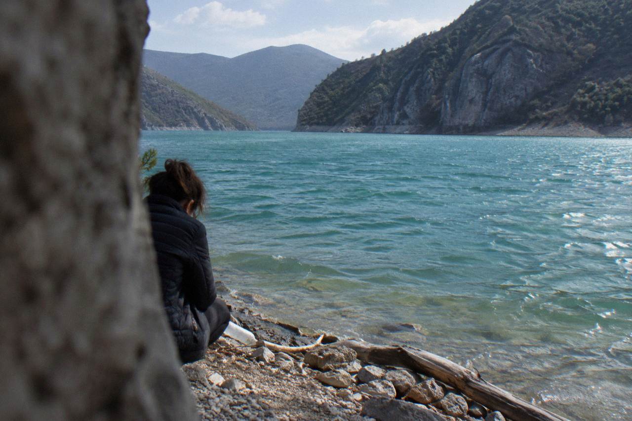 A turquoise mountain reservoir ringed by steep rocky hills under a clear sky