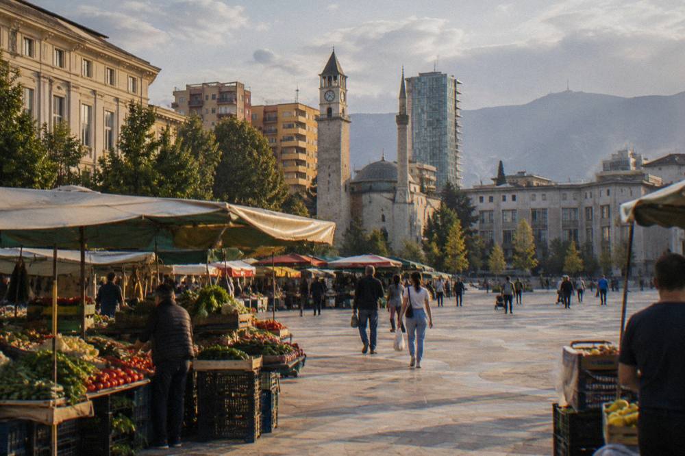 Fresh produce stalls under awnings at an open-air market in Tirana
