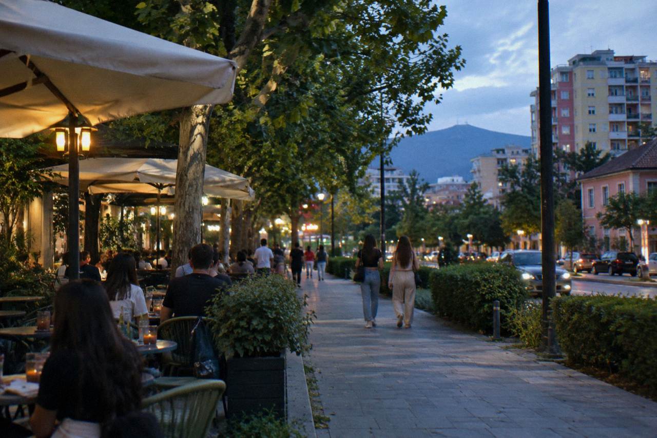 Evening lights and outdoor tables along a tree-lined street in the Blloku quarter of Tirana