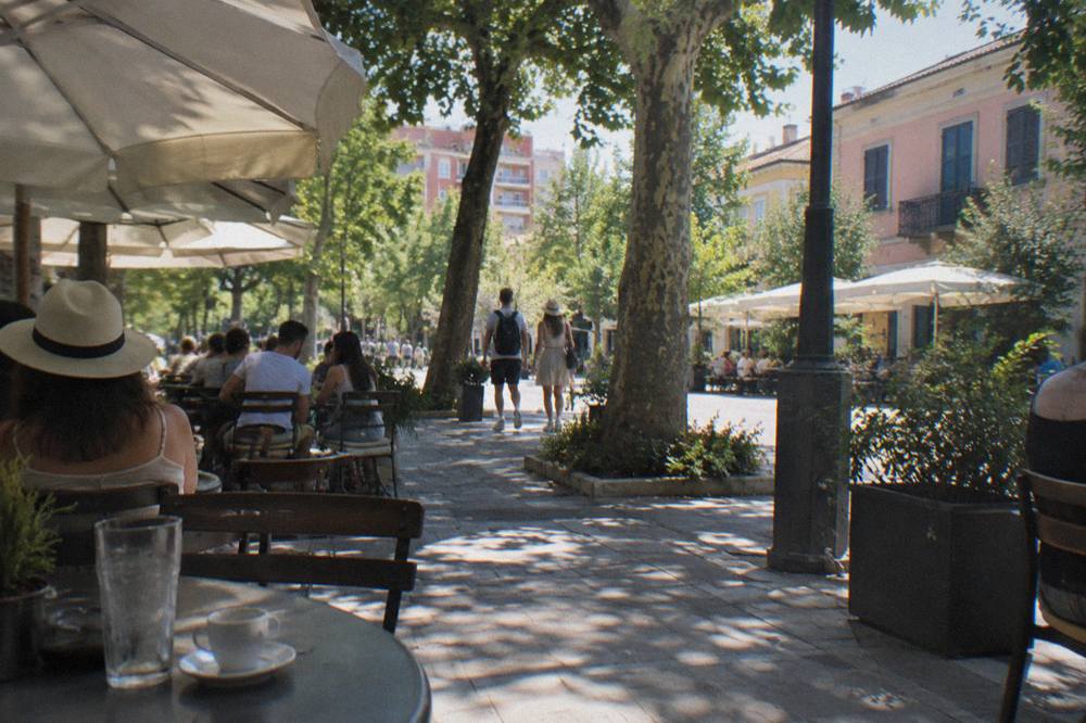 A shaded street with cafe tables in the Blloku quarter of Tirana on a summer evening