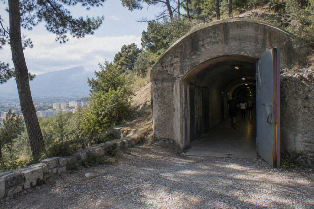 A long dim underground corridor with steel doors and exhibition lighting inside a bunker museum