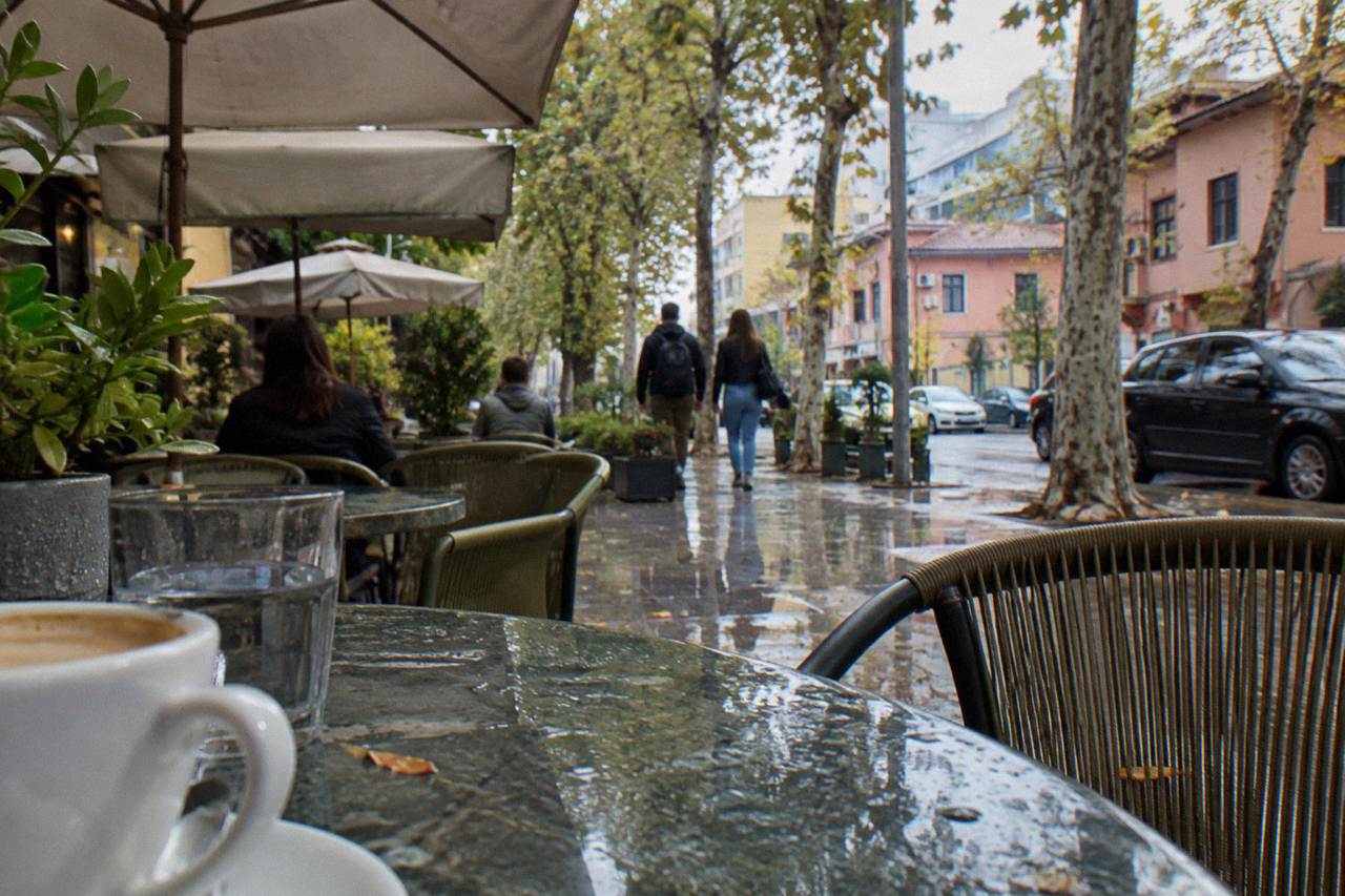 Cafe tables and leafy trees along a street in the Blloku district of Tirana