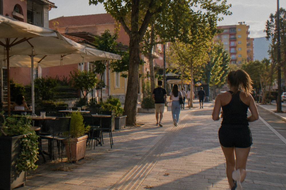 People walking past low villas and apartment blocks on a quiet Blloku street