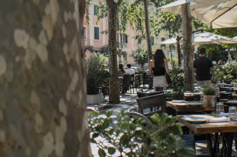A restaurant terrace in Blloku with tables set for dinner under trees