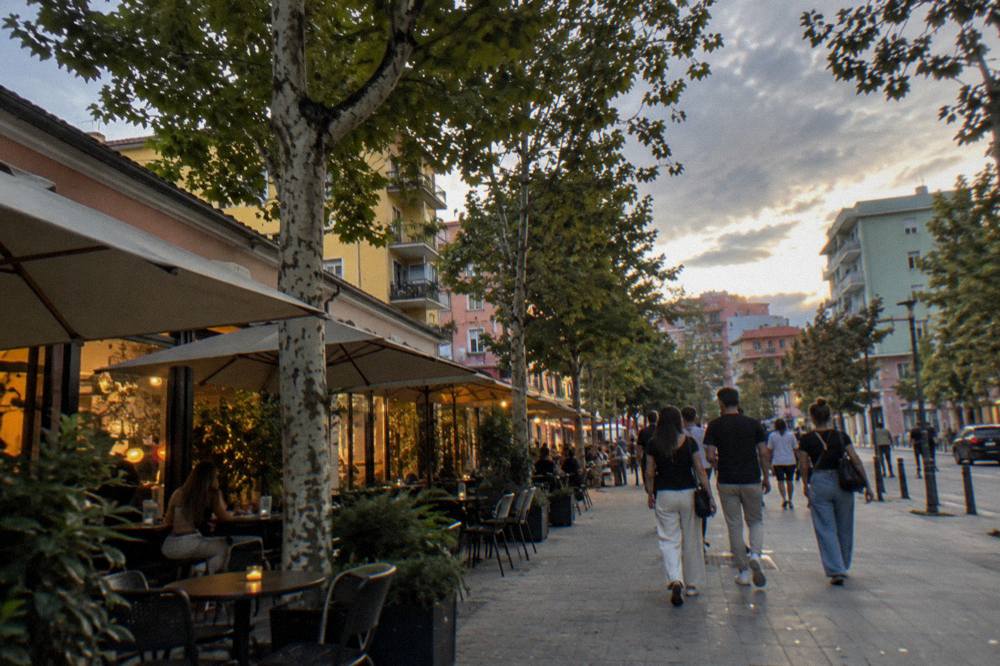 Evening light on a Blloku street with lit cafe windows and pedestrians