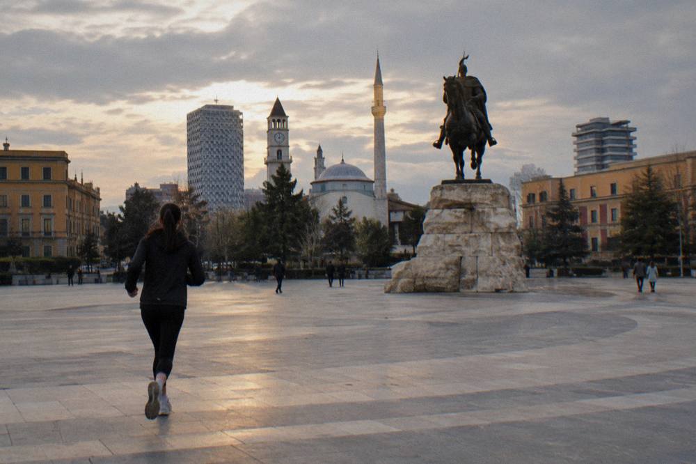 The equestrian statue of Skanderbeg lit in the evening with the mosque minaret behind it