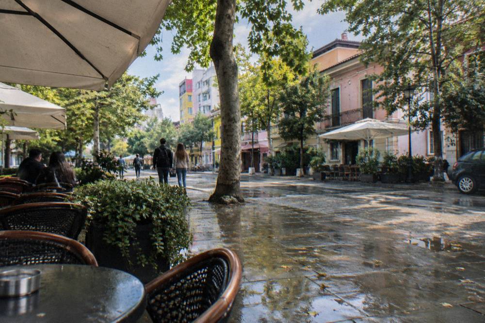 Cafe tables and leafy trees on a quiet street in Tirana's Blloku quarter