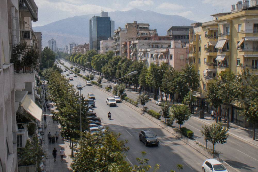 A long city street with shops and apartment buildings in western Tirana
