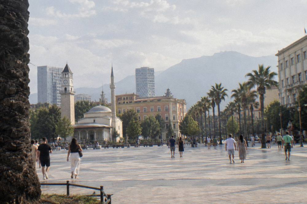Palm-lined boulevard in Tirana with people strolling on a warm evening