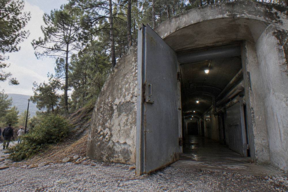 A dim corridor inside Bunk'Art 1 with steel doors and pipes running along the concrete walls