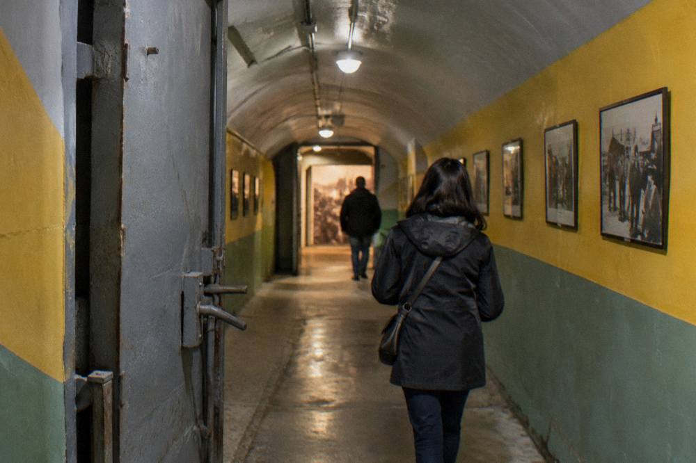 A visitor walking through a brightly painted corridor of the bunker museum toward a lit exhibition room
