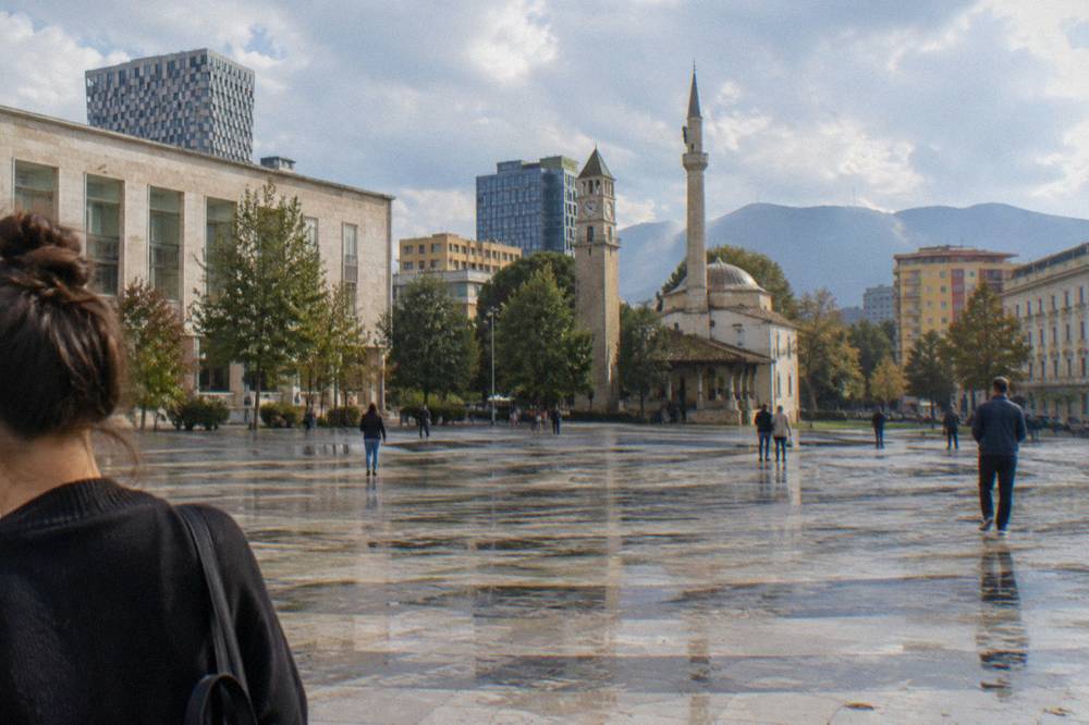 City street in central Tirana with modern buildings around an old stone structure