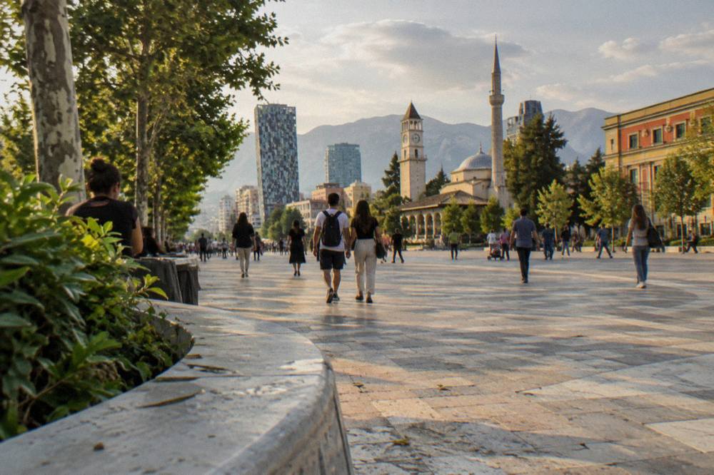 People strolling on a leafy boulevard in central Tirana in the afternoon