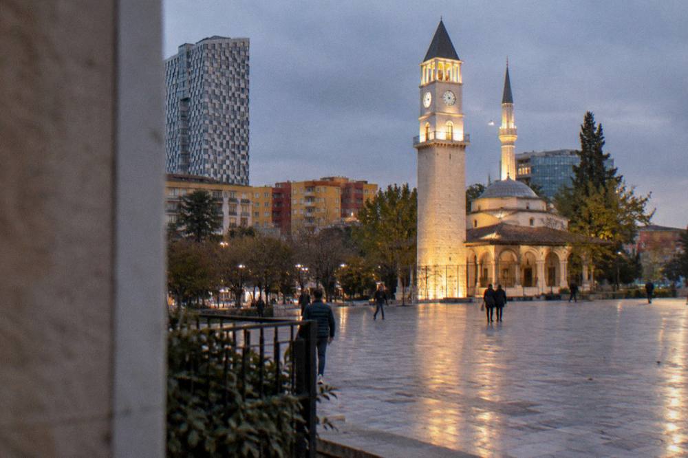 The Clock Tower and mosque lit up at dusk with the illuminated surface of Skanderbeg Square below