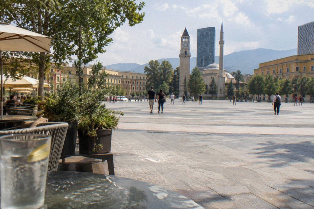 A paved pedestrian street in central Tirana with cafes and planted trees