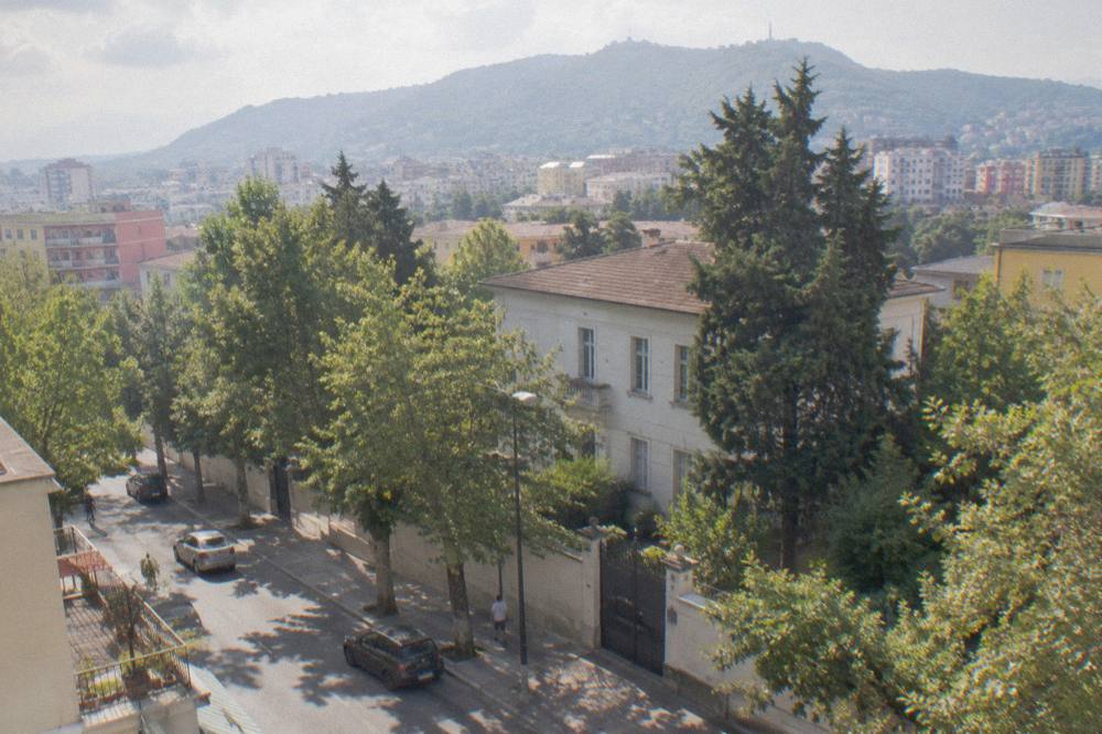 A green hillside rising above city rooftops toward a mountain ridge