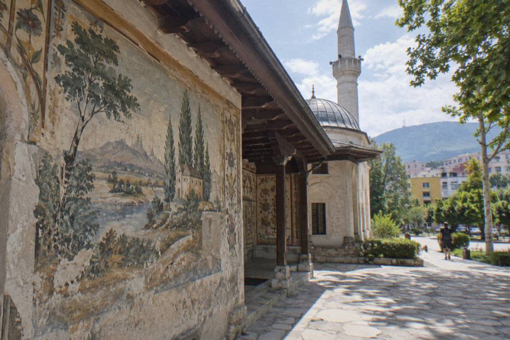 Detail of painted frescoes on the mosque porch showing trees and a landscape scene
