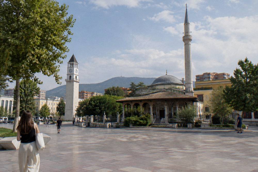 View across the pedestrian surface of Skanderbeg Square toward the mosque and tower