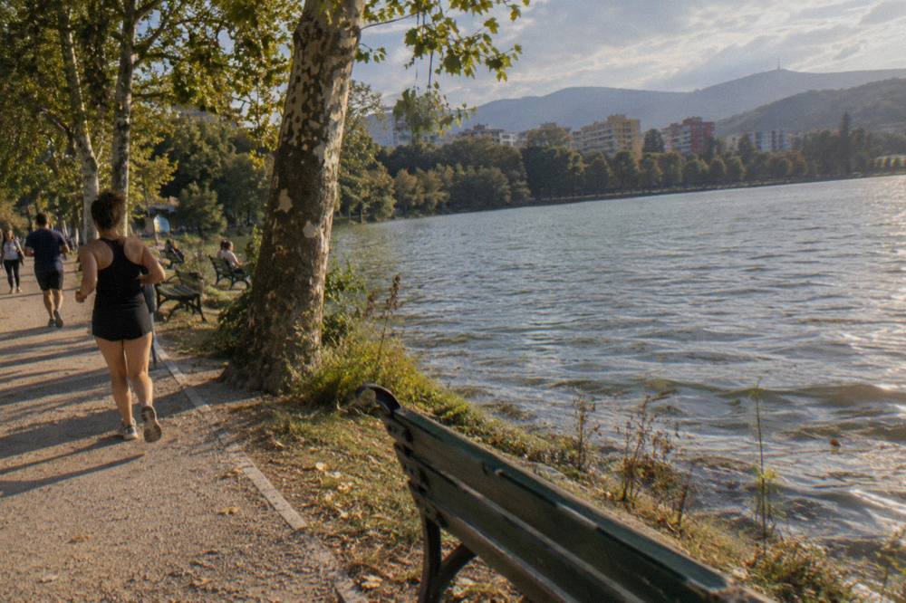 Runners and walkers on the gravel loop path around the Artificial Lake in Tirana