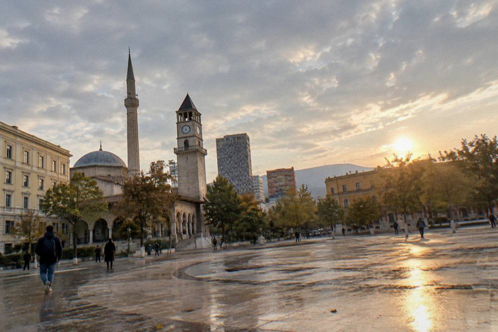 The Namazgah Mosque dome rising above tree-lined streets in Tirana at golden hour