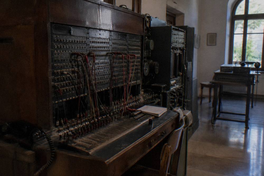 An old telephone switchboard and wiretapping equipment displayed in a dim museum room
