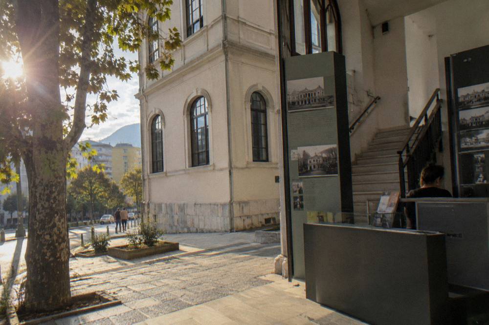 A museum ticket desk with information panels and a stairway leading to the upper floor