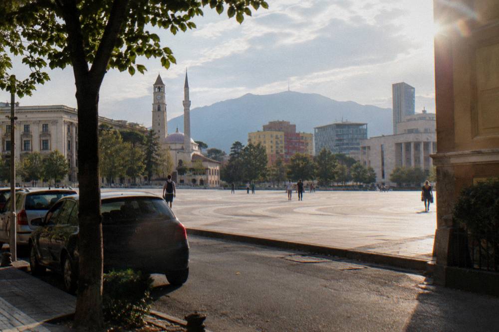 A quiet central Tirana street with parked cars and older villa facades near the museum