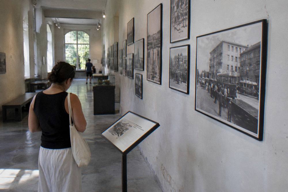 A visitor reading an information panel in a museum corridor with archival photographs