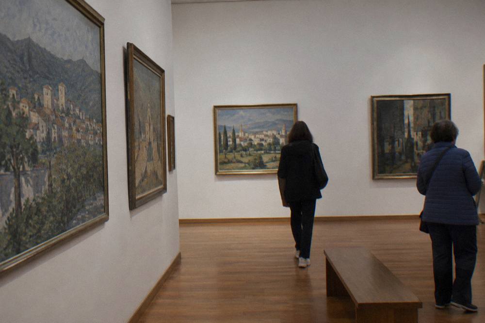 Paintings hanging on a gallery wall in a museum interior with wooden floors