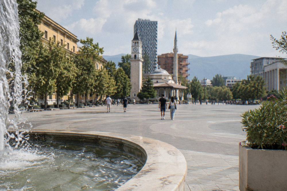 Wide pedestrian boulevard in Tirana lined with trees and public buildings