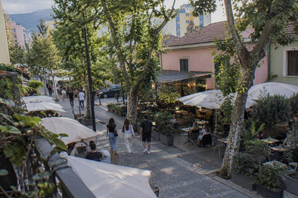 Cafe tables and leafy streets in the Blloku quarter of Tirana on a sunny afternoon