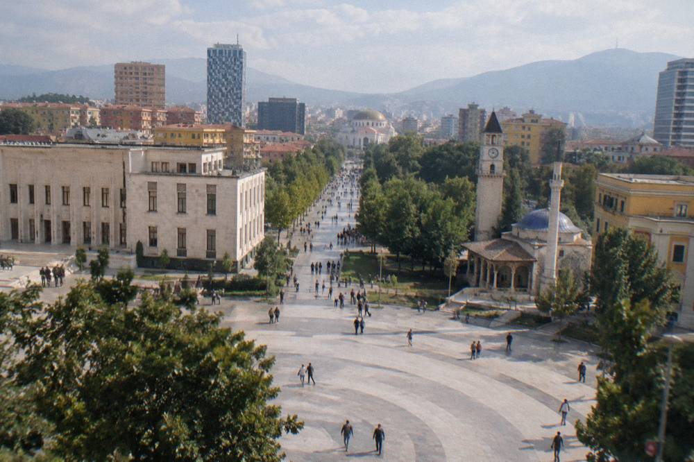 People walking along a central Tirana street toward the cathedral dome