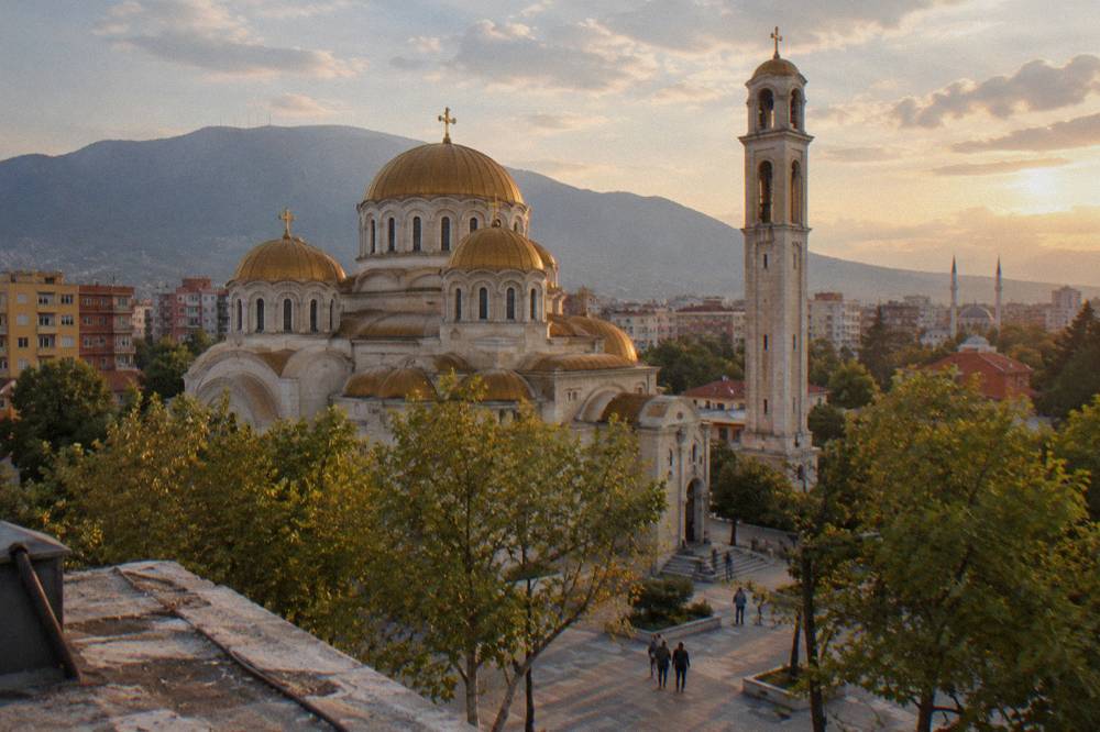The domes of the Orthodox cathedral and distant minarets seen from a rooftop in Tirana