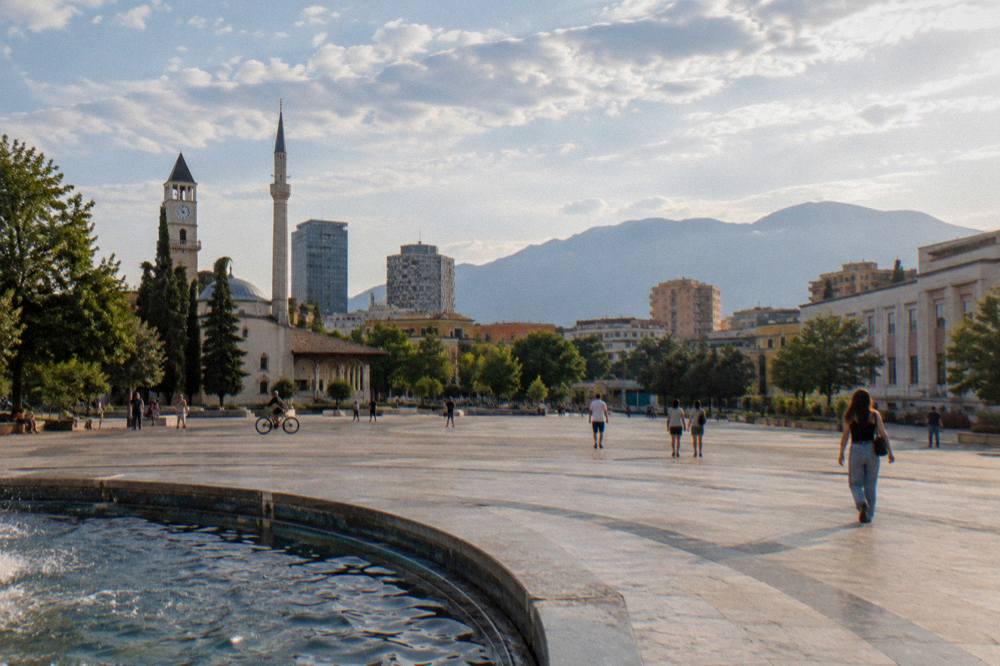 A evening view of central Tirana with church domes and mountains beyond the city