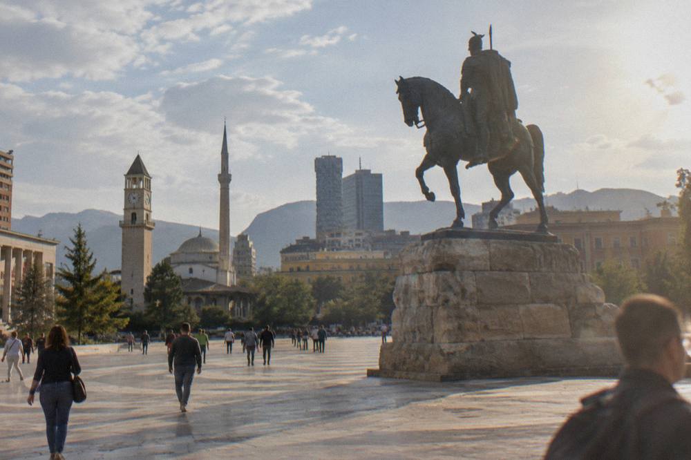 The equestrian statue of Skanderbeg at the centre of the square with people walking across the paving