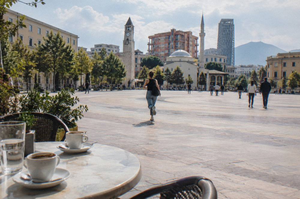 An outdoor cafe table with coffee cups on a pedestrian street near the square