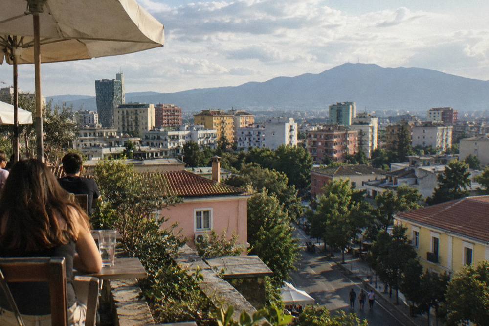 The rooftops of Blloku and central Tirana seen from above with the mountain ridge in the far distance