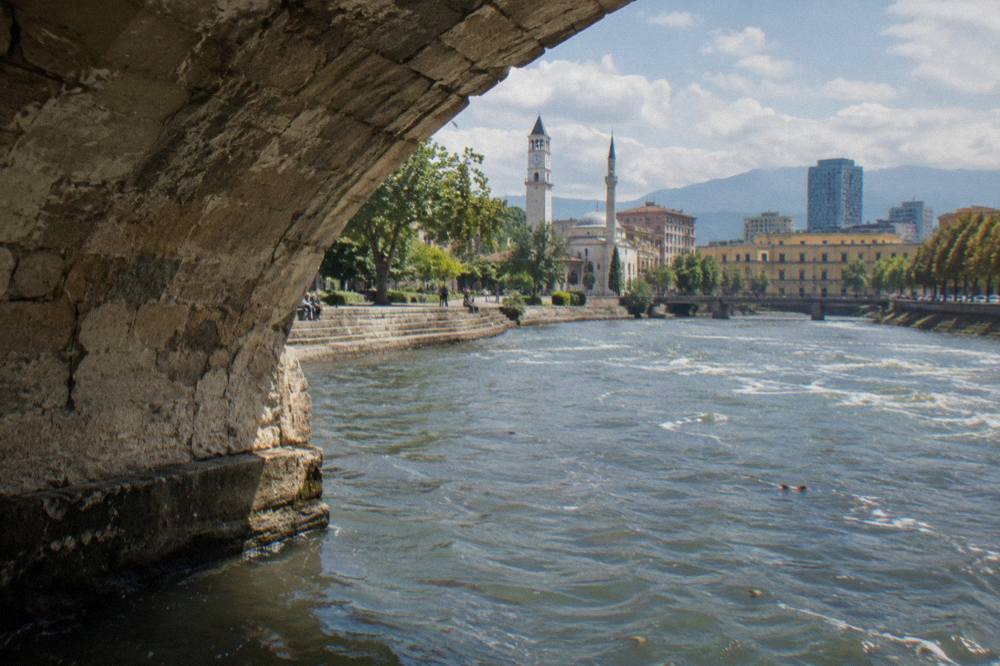 Close view of the weathered stone arch and vaulted underside of an old bridge in Tirana