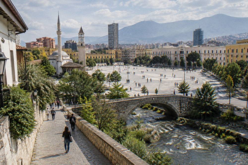 A pedestrian street in Tirana with old stone paving leading toward an old stone bridge