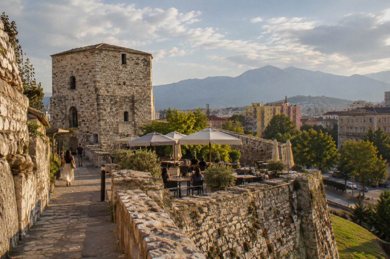 Stone walls and towers of Tirana Castle with a lit pedestrian lane inside