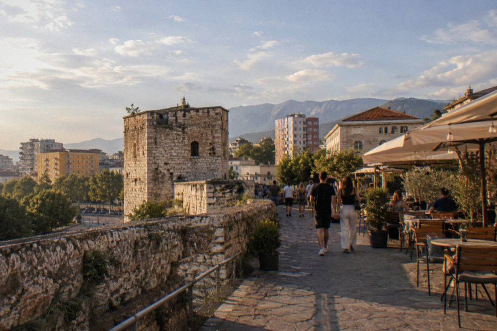 Pedestrians walking through the castle lane past restaurant terraces in the evening