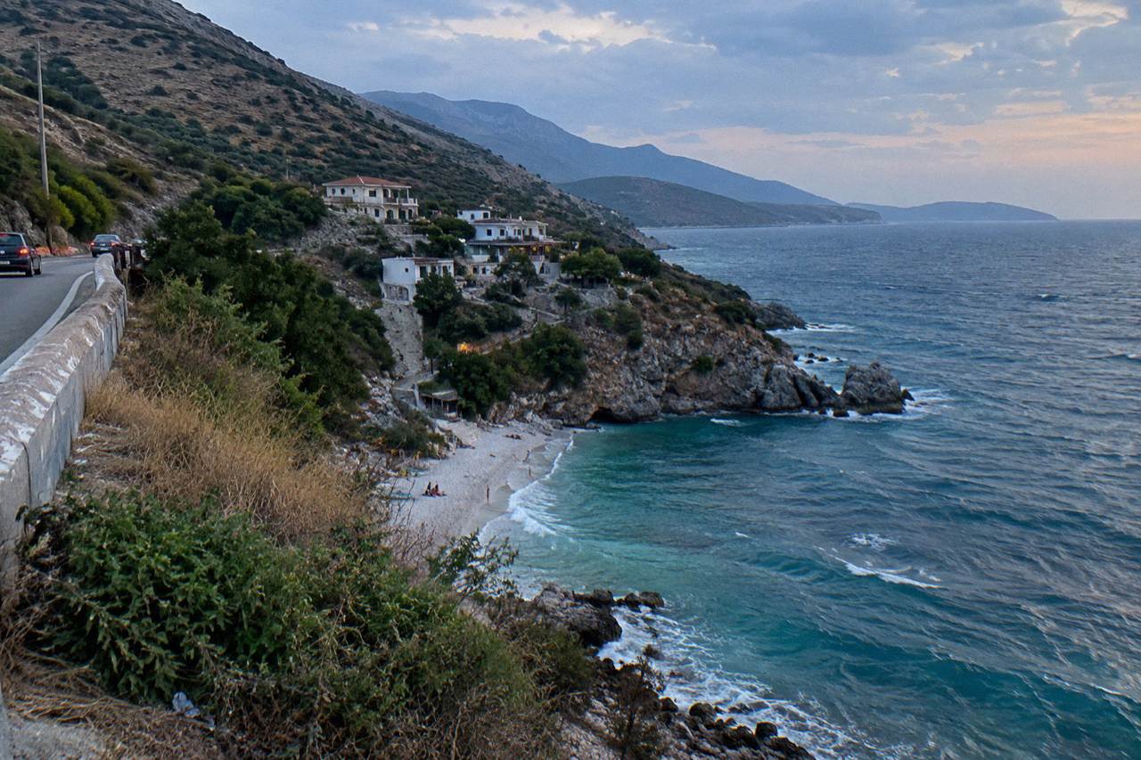 A winding mountain road above a green coastline with the sea in the distance