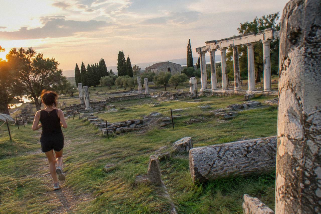 Stone ruins and columns of an ancient archaeological site on a grassy hillside